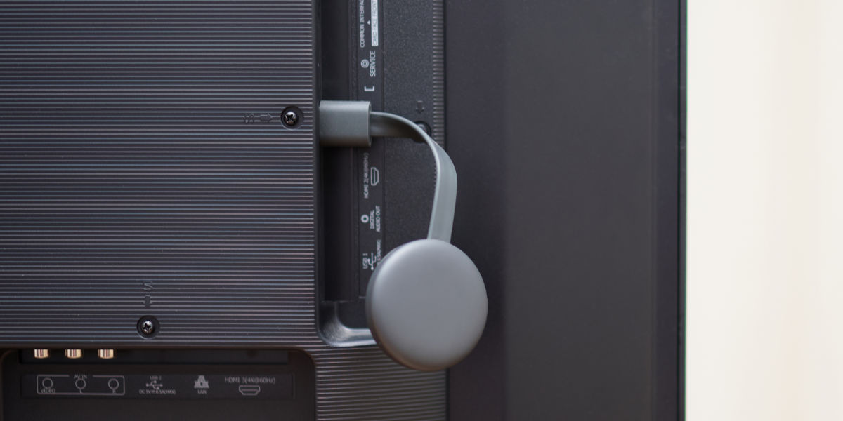 Chromecast dongle plugged into the HDMI port on the back of a TV