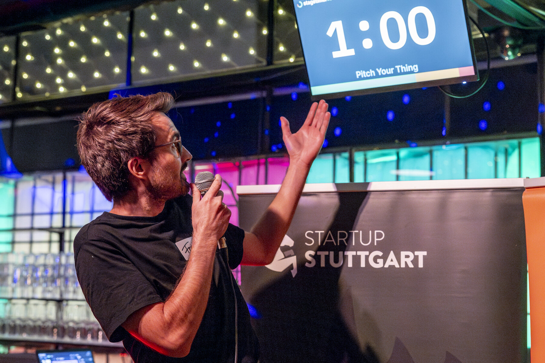 Speaker at Startup Stuttgart Gründergrillen pitch event with Stagetimer showing 1:00 remaining and the message 'Pitch Your Thing'